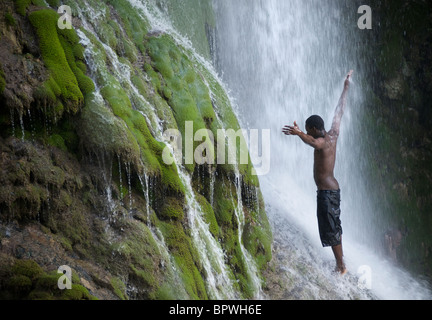 Un praticien Voodoo lève son bras comme il vénère sous une cascade à l'assemblée annuelle de saut d'eau festival vaudou en Haïti. Banque D'Images