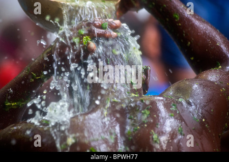 Un praticien Voodoo verse de l'eau sur sa tête pendant le saut d'eau annuel festival vaudou en Haïti. Banque D'Images