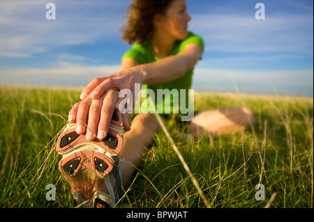 Une coureuse s'étend et se réchauffe dans l'herbe avant qu'une longue Banque D'Images