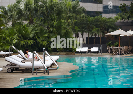 Woman relaxing by piscine du Grand Hyatt Hotel, Hong Kong, Chine Banque D'Images