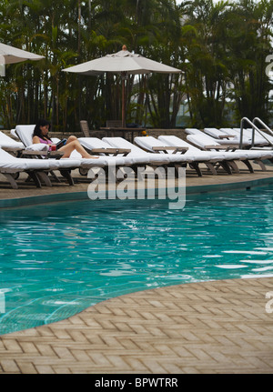 Woman relaxing by piscine du Grand Hyatt Hotel, Hong Kong, Chine Banque D'Images