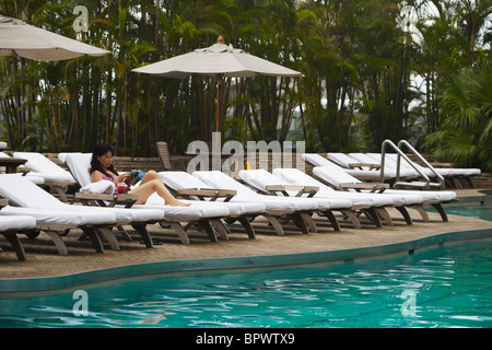 Woman relaxing by piscine du Grand Hyatt Hotel, Hong Kong, Chine Banque D'Images