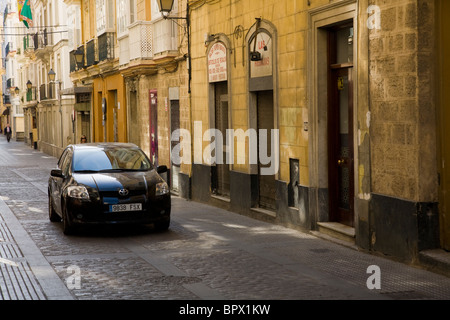 Traditionnel espagnol typique rue pavées / Rue / Route, avec une Toyota voiture conduire le long de celle-ci. Cadix, Espagne. Banque D'Images