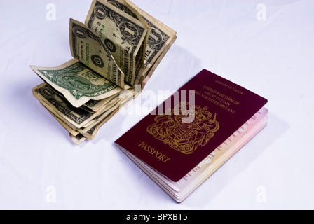 Un passeport du Royaume-Uni portant à côté d'un tas de projets de Dollars américains utilisés Banque D'Images
