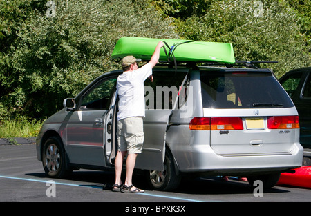 Un homme fixant son kayak sur le rack sur le dessus de son SUV wagon. Banque D'Images