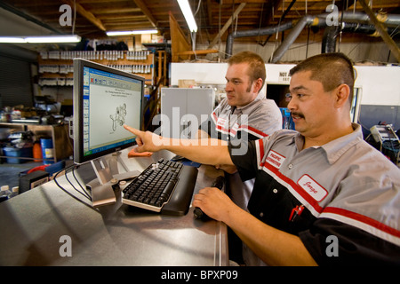 La vérification d'une image schématique d'un moteur d'automobile sur un écran d'ordinateur, deux mécaniciens en Californie du Sud indépendant Banque D'Images