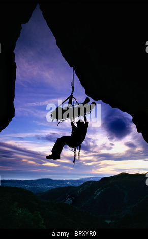 Recherche et sauvetage climber hanging from litière, sunset silhouette, Santa Barbara, CA Banque D'Images