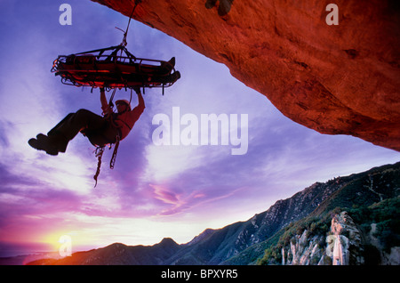 Recherche et sauvetage climber hanging from litière, au coucher du soleil, Santa Barbara, CA Banque D'Images