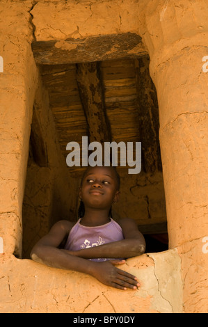 Fille à travers la fenêtre d'un cas typique à étage, M'connexion lomp, Casamance, Sénégal Banque D'Images