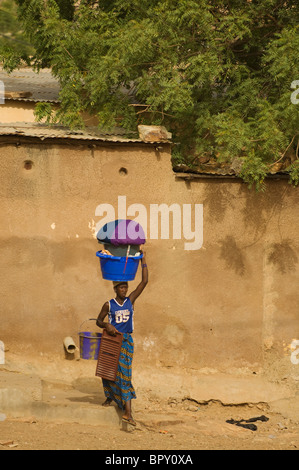Femme portant une laverie pour le fleuve Sénégal, scène de rue, Bakel, Sénégal Banque D'Images