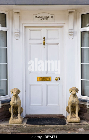 Panneaux en bois peint en blanc, porte d'entrée de maison avec le bouton laiton heurtoir letterbox et pierre hound chiens assis à l'extérieur Banque D'Images