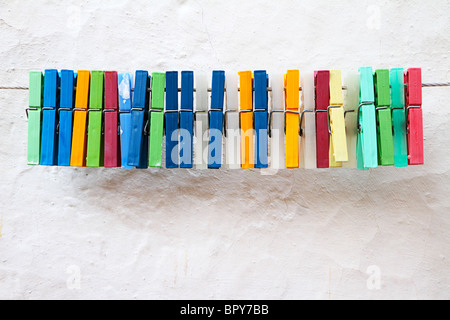 Ligne de vêtements blancs en plastique chevilles contre mur Banque D'Images