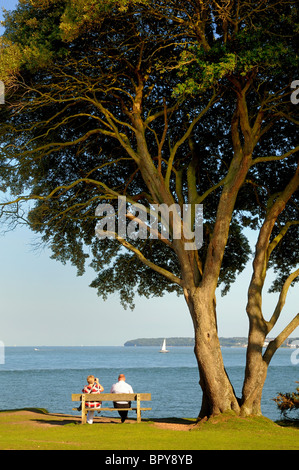 Deux personnes assis sur un banc en regardant le Solent et l'île de Wight Banque D'Images