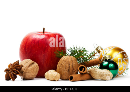 Pomme rouge, l'anis étoilé, quelques écrous, d'or et de boules de Noël vert et une branche sur fond blanc Banque D'Images