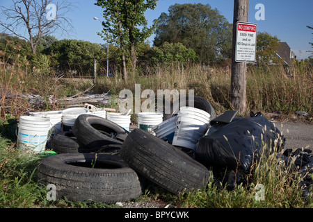 Detroit, Michigan - les vieux pneus et autres déchets sont déversés dans une ruelle à côté d'un signe d'avertissement des pénalités pour dépôt illégal. Banque D'Images