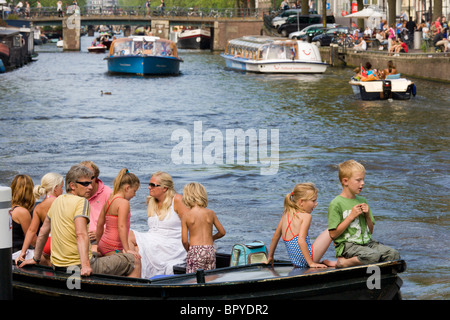 Amsterdam en bateau. Famille avec enfants en petit bateau ouvert sur le Canal Prinsengracht, avec canal bateaux d'excursion dans l'arrière-plan. Banque D'Images