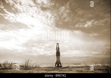 Caucasian man doing yoga wavecrest sur une plage. Banque D'Images