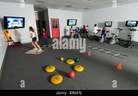 Les enfants à exercer sur les vélos connecté à la télévision. Banque D'Images