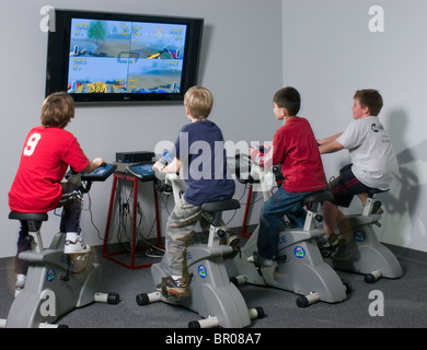 Les enfants à exercer sur les vélos connecté à la télévision. Banque D'Images