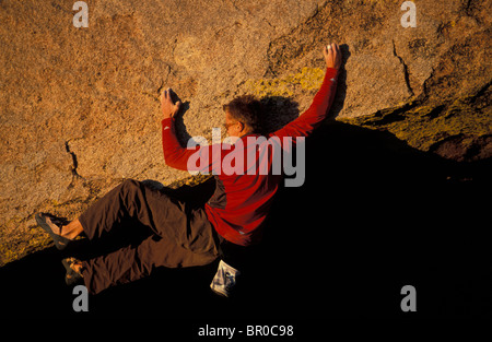 Un male rock climber bouldering en soirée sur une voie d'escalade en surplomb. Banque D'Images