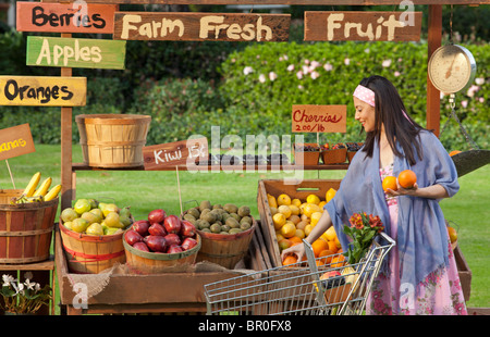 Woman with stand de fruits avec chariot d'épicerie Banque D'Images