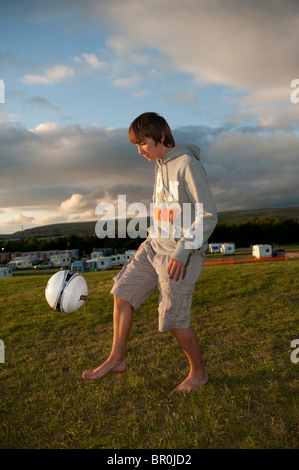 Un garçon coups de football sur le site de camping au la lumière au cinéma, Ebbw Vale 2010 Banque D'Images