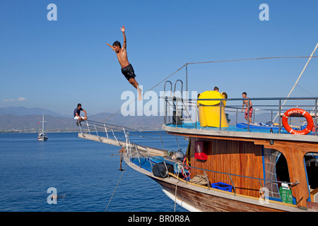 Adolescent de sauter un bateau pendant un voyage en bateau de Fethiye à 12 îles, la mer Egée Turque, Turquie Banque D'Images