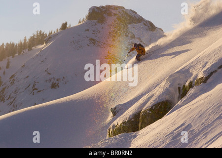 Un homme ski par un arc-en-ciel en poudreuse sur sommet de donner, en Californie. Banque D'Images