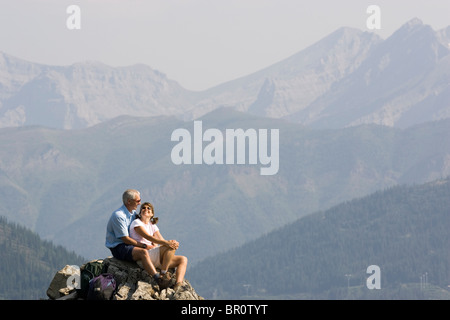 La mi-aged couple profiter vue depuis le pic d'une montagne dans le lézard éventail près de Fernie, en Colombie-Britannique. Banque D'Images