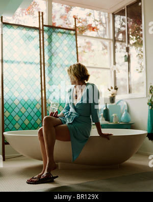 Femme assise sur le bord de la baignoire Banque D'Images