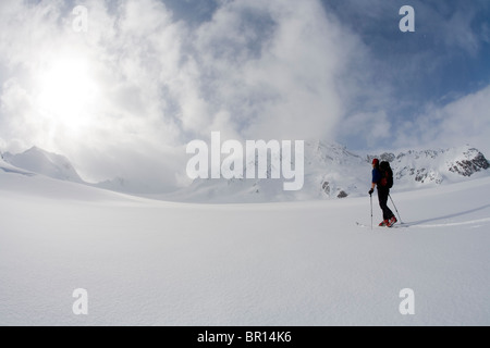 La skieuse de l'arrière-pays traverse sous feu glacier jour ciel d'orage. (Grand angle) Banque D'Images