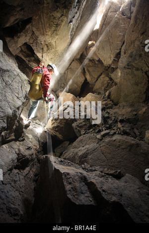 Un spéléologue descend dans une chambre souterraine, allumé la lumière du jour dans les Montagnes Blanches, sur l'île de Crète. Banque D'Images