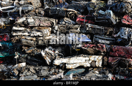 Un grand tas de voitures de ferraille concassées attendent d'être ramassées sur le quai avant d'être recyclées. Banque D'Images