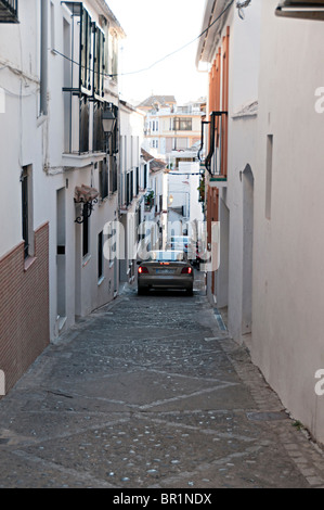 Une étroite rue pavée, à Estepona espagne avec une voiture roulant vers le bas il Banque D'Images