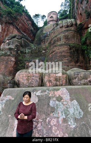 Femme prie en face de giant orteils du Dafo ou Grand Bouddha, le Shan, province du Sichuan, Chine Banque D'Images