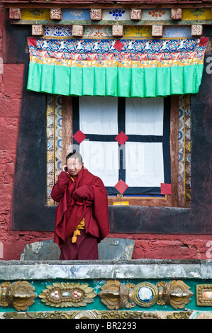 Moine bouddhiste tibétain parle sur téléphone cellulaire à l'extérieur de temple principal, Monastère Tagong, province du Sichuan, Chine Banque D'Images