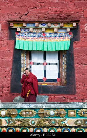 Moine bouddhiste tibétain parle sur téléphone cellulaire à l'extérieur de temple principal, Monastère Tagong, province du Sichuan, Chine Banque D'Images