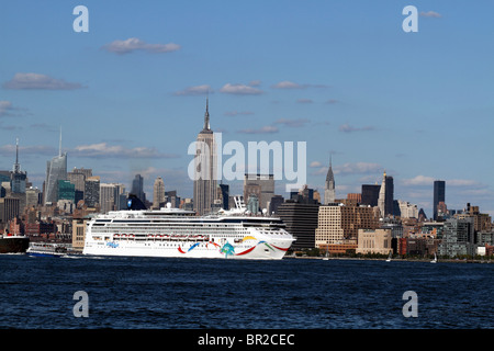 Un navire de croisière, laissant Mid-town Manhattan pour commencer son voyage et passer sous l'Empire State Building. New York City, USA Banque D'Images