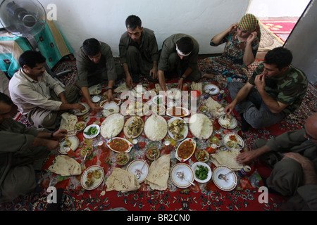 Un groupe de combattants kurdes des forces de défense populaires HPG, l'aile militaire du PKK du Parti des travailleurs du Kurdistan, mangeant de la nourriture traditionnelle kurde dans une maison sûre dans un village rural dans les montagnes de Qandil, une zone montagneuse près de la frontière avec l'Iran en Irak Banque D'Images