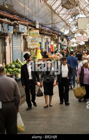 Deux hommes et une femme orthodoxe shopping dans le marché Mahane Yehuda, Jérusalem, Israël Banque D'Images