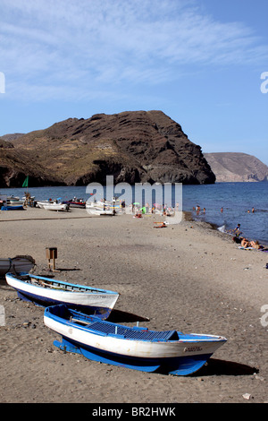 Vue verticale de la plage de las Negras, Espagne avec bateaux de pêche bleu et blanc en premier plan et le noir promontoire rocheux à distance Banque D'Images