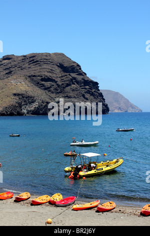 Vue verticale de la plage de las Negras montrant de couleur jaune et rouge des kayaks sur la plage et noir promontoire rocheux en arrière-plan Banque D'Images