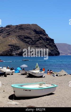 Vue verticale de la plage de las Negras, Espagne avec bateau de pêche en premier plan et le noir promontoire rocheux à l'arrière ; Deep Blue Sea sky Banque D'Images