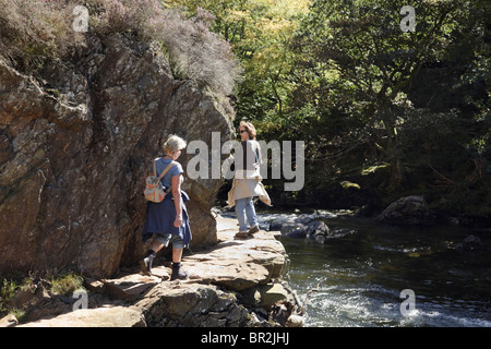 Les femmes touristes marcher sur l'éperon rocheux étroit sur le chemin des pêcheurs par la gorge de la rivière Glaslyn Afon dans Aberglaslyn Pass. , Beddgelert, Snowdonia au Pays de Galles, Royaume-Uni. Banque D'Images