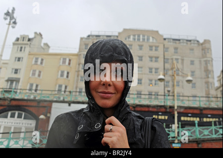 Jeune femme portant des bois et de l'enveloppe dans la pluie sur le front de mer de Brighton UK Banque D'Images