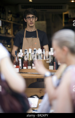 Un vendeur de montres clients potentiels à son magasin sur la Rue Mouffetard, un célèbre marché alimentaire à Paris Banque D'Images