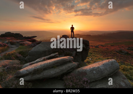 Silhouette d'une femme debout sur un éperon rocheux de Owler Tor près de Hathersage dans le Peak District de Derbyshire, Angleterre. Banque D'Images