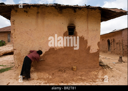 Le plâtrage de boue femme sa maison, Mtae, ouest de la Tanzanie, Montagne Usambara Banque D'Images