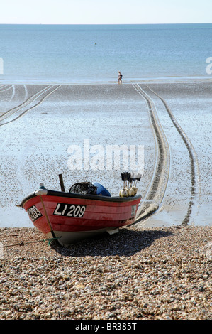 Petit bateau de pêche d'être tiré par une corde unique à travers une plage de sable à marée basse et sur une zone de galets à Bognor Regis Resort Banque D'Images