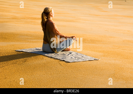 Une femme pratiquant le yoga sur une plage au parc national Abel Tasman. L'île du Sud, Nouvelle-Zélande. Banque D'Images